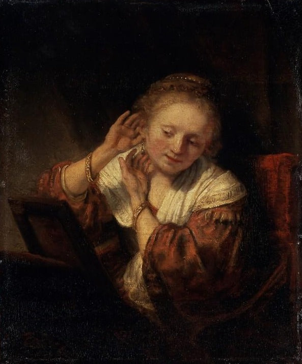 Jeune femme essayant des boucles d'oreilles - Rembrandt van Rijn
